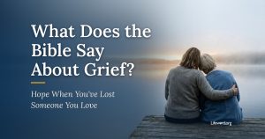 Two women sit close together on a wooden dock, one resting her head on the other's shoulder, looking out at a misty lake at dawn. Title card: What Does the Bible Say About Grief? Hope When You've Lost Someone You Love.