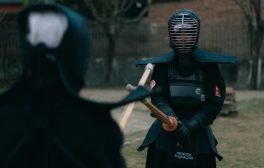 Two kendo practitioners sparring outdoors in traditional armor, focusing on technique and discipline.