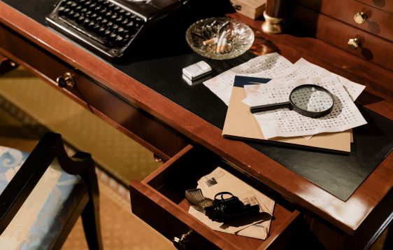 A moody vintage detective's desk with typewriter, magnifying glass, and secret documents.