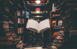view of floating open book from stacked books in library