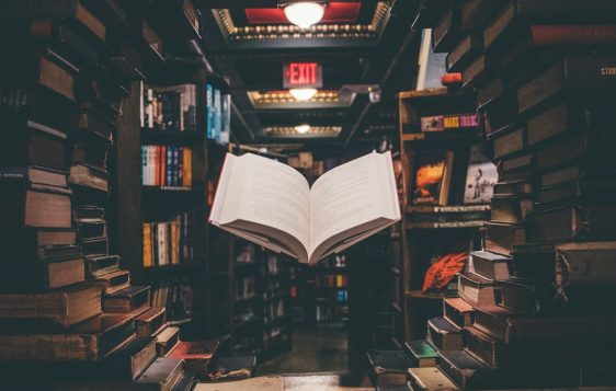 view of floating open book from stacked books in library