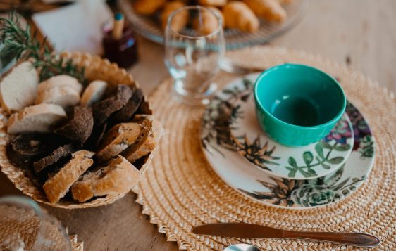 Cozy breakfast setup with various breads and ceramic tableware on a woven placemat.