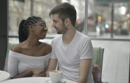 kobieta z czarnymi włosami i mężczyzna w białej koszulce siedzący przy stole w kawiarni na randce