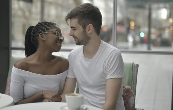 kobieta z czarnymi włosami i mężczyzna w białej koszulce siedzący przy stole w kawiarni na randce